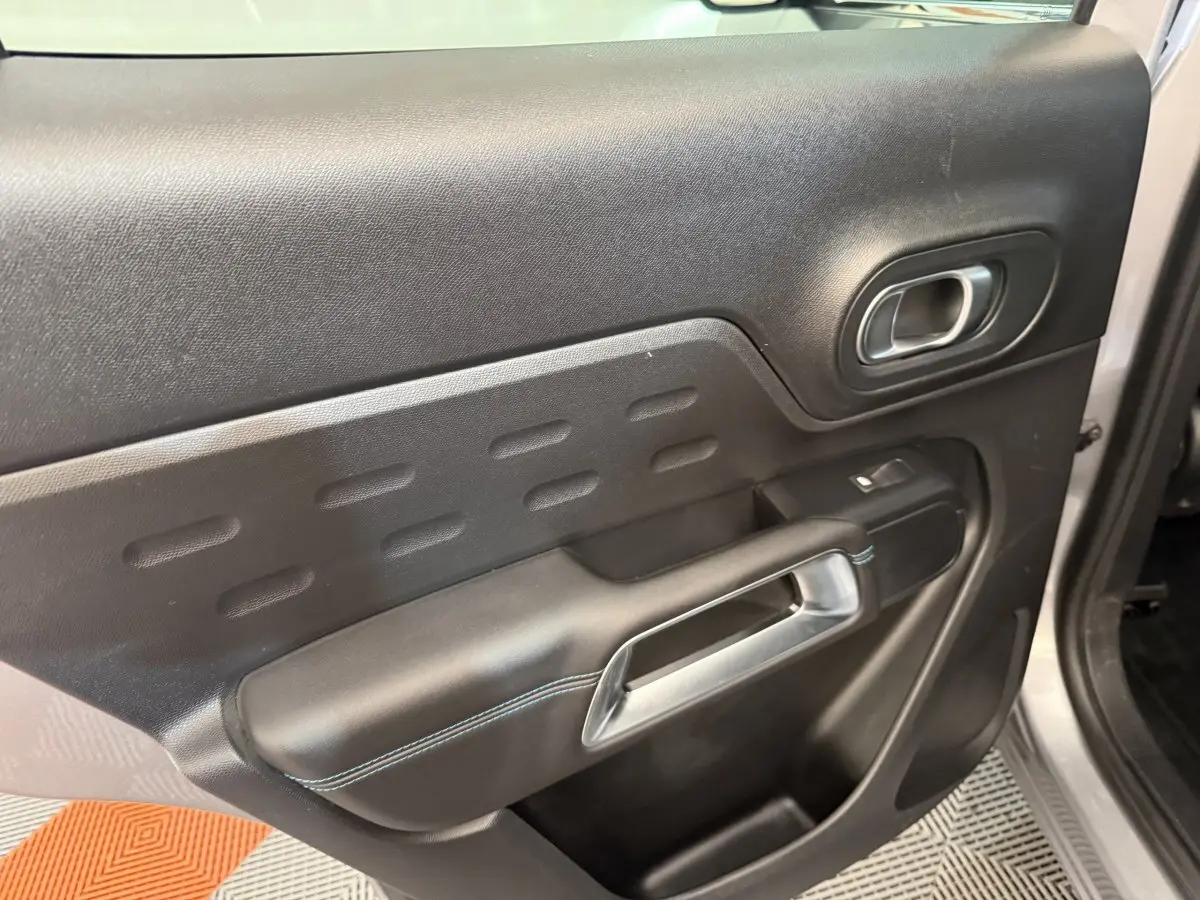 Vue rapprochée de la porte avant droite du Citroën C5 Aircross gris clair, avec poignée argentée et surpiqûres bleues.