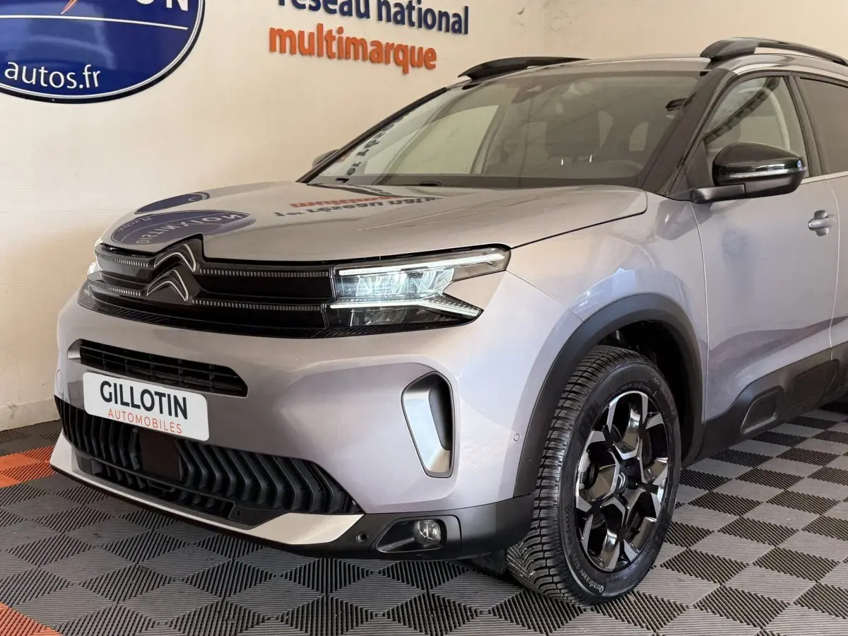 Vue 3/4 avant droit du Citroën C5 Aircross gris clair avec calandre noire et jantes noires brillantes.