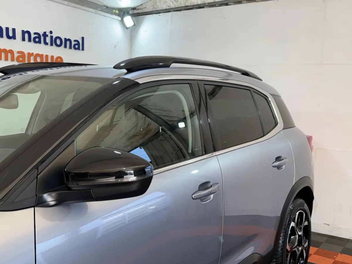 Vue de profil côté gauche sur le CITROEN C5 AIRCROSS gris clair avec rétroviseur noir et barres de toit noires.