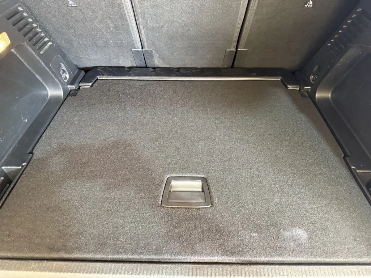 Vue rapprochée du coffre gris clair du Citroën C5 Aircross 2023 avec plancher plat et poignée centrale intégrée.