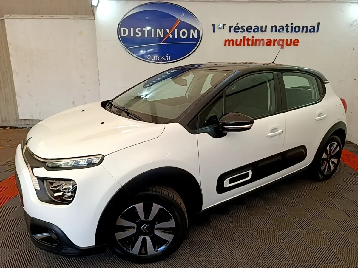 Vue 3/4 avant droite d'une Citroën C3 blanche avec protections latérales noires et jantes bicolores.