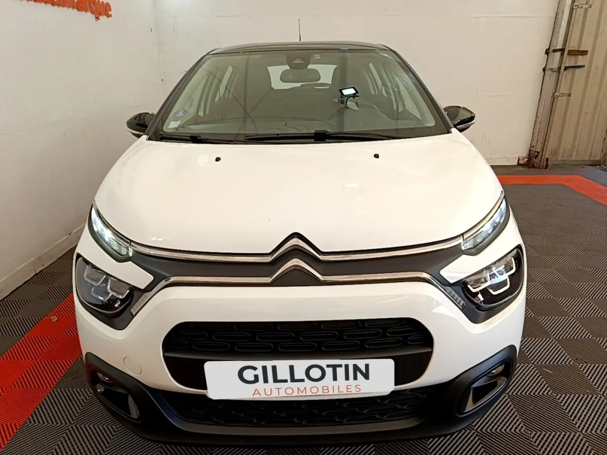Vue avant d'une Citroën C3 blanche 2021 avec phares LED et calandre noire dans un showroom.