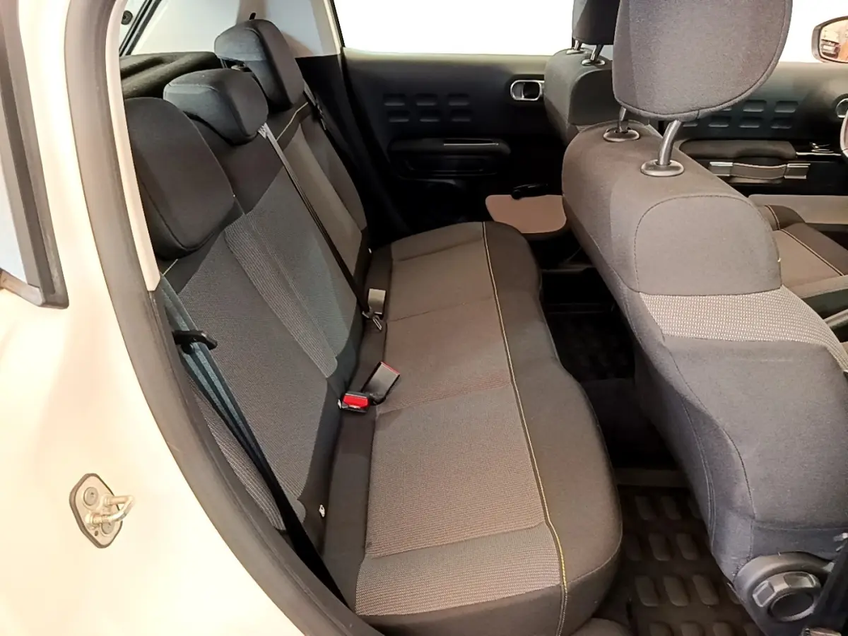 Vue intérieure côté gauche montrant la banquette arrière grise et les sièges avant d'une Citroën C3 blanche 2021.