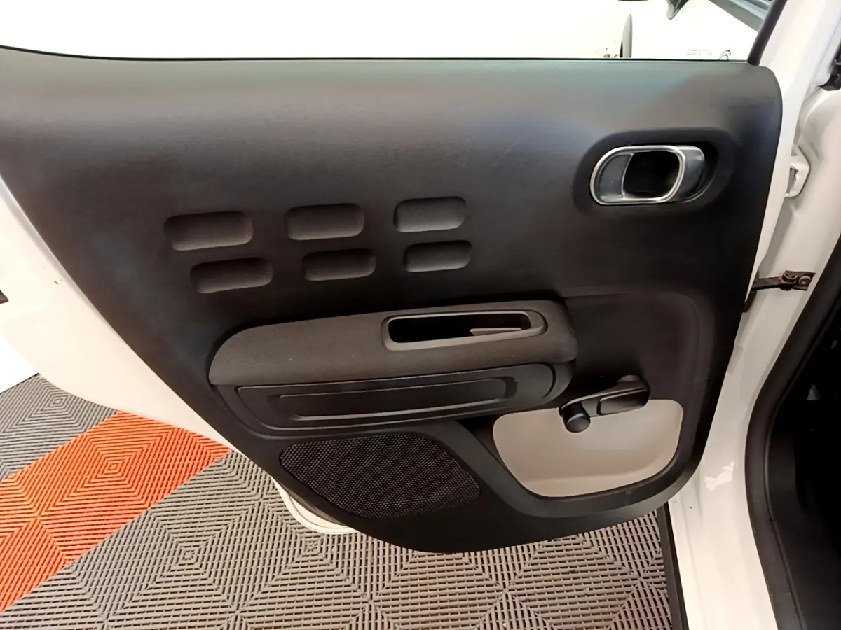 Vue intérieure de la porte arrière gauche blanche d'une Citroën C3 2021 avec poignée manuelle et haut-parleur intégré.