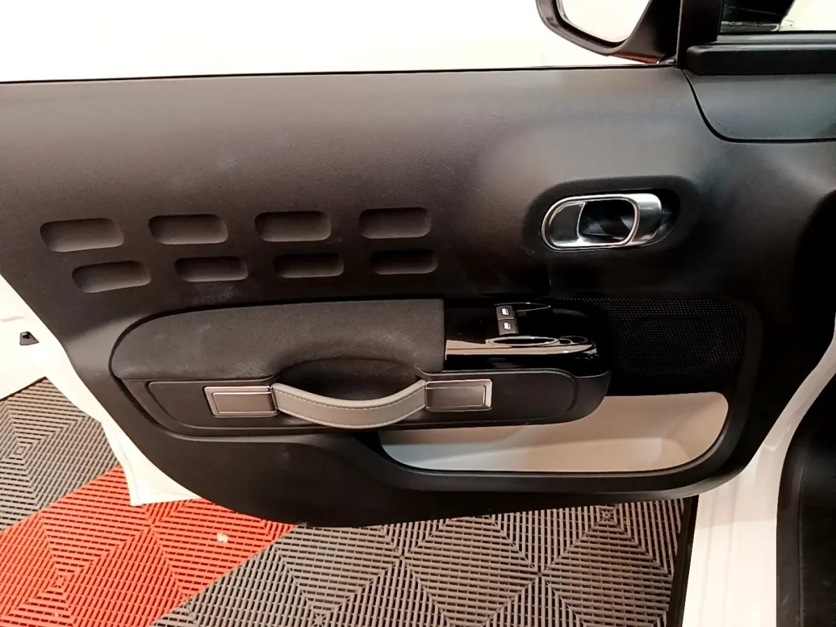 Vue intérieure de la porte avant gauche blanche d'une Citroën C3 2021 avec poignée noire et détails chromés.