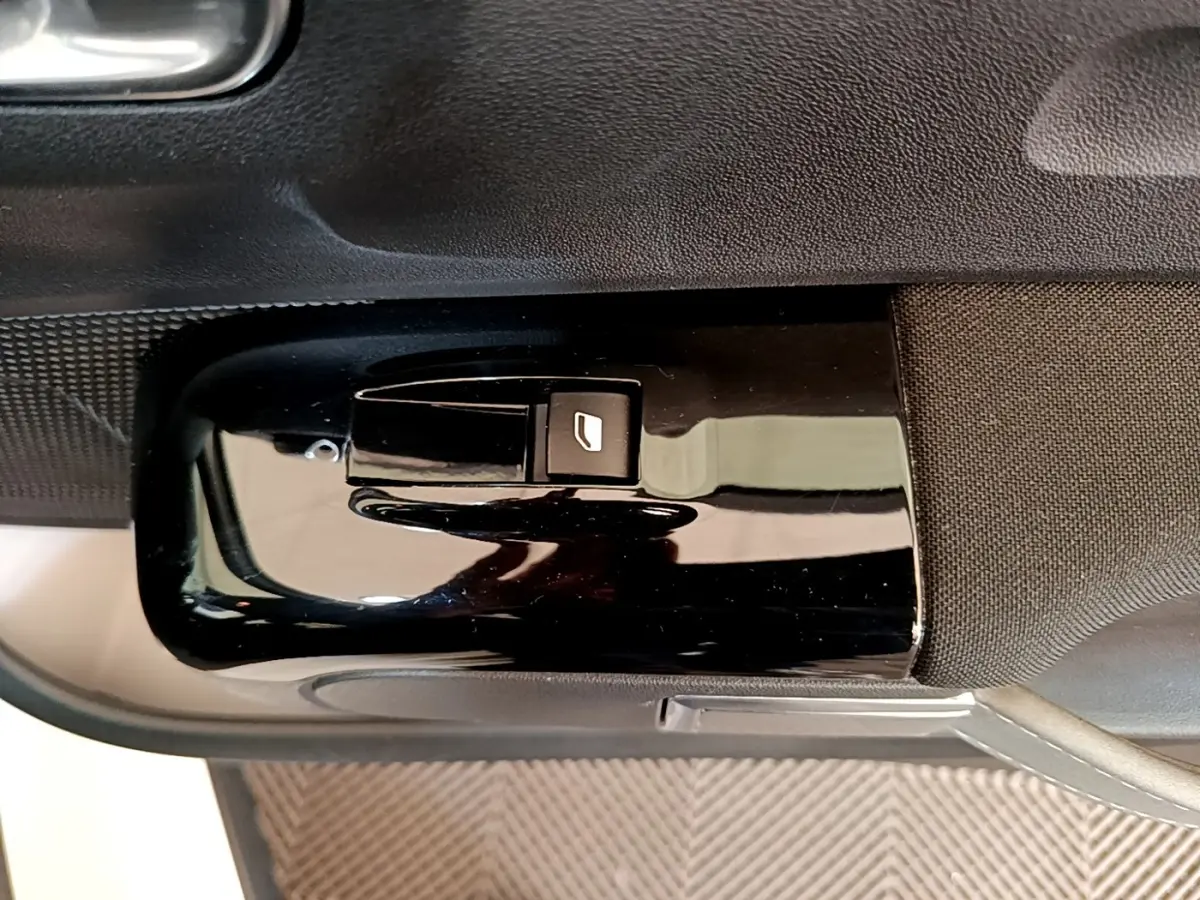 Bouton de commande de lève-vitre électrique sur la porte intérieure côté conducteur d'une Citroën C3 blanche.