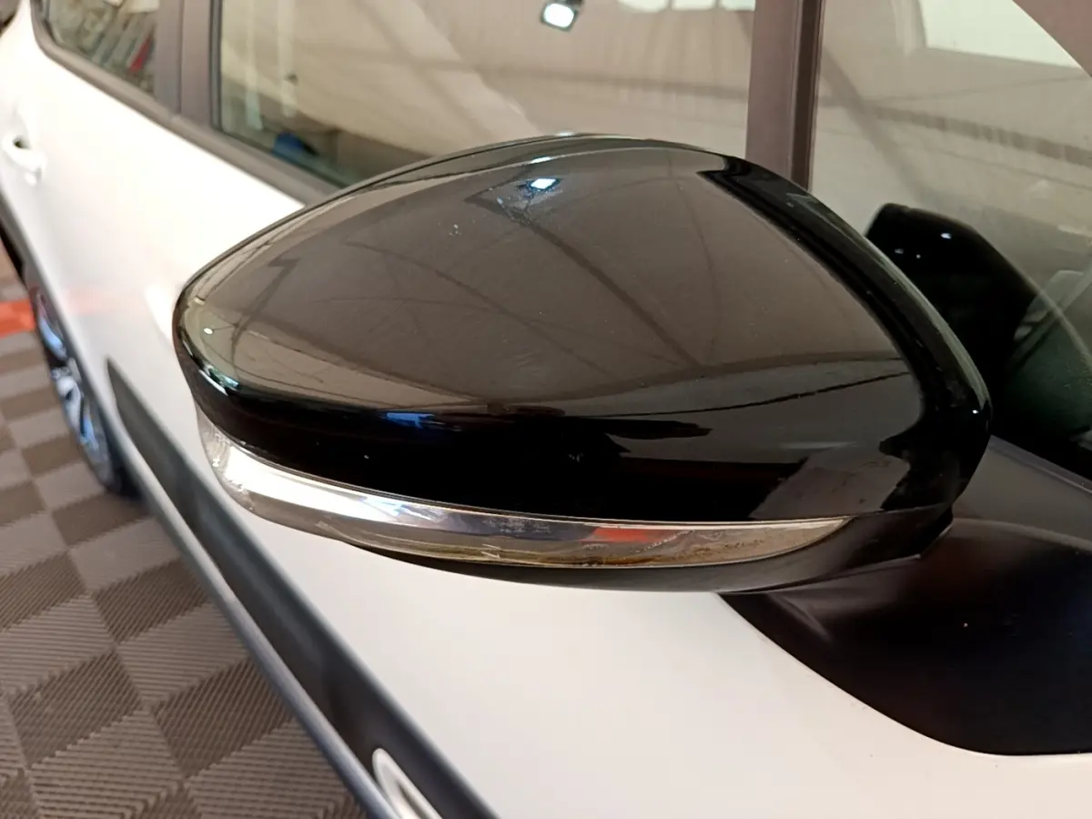 Rétroviseur noir en gros plan côté gauche d'une Citroën C3 blanche, avec clignotant intégré.