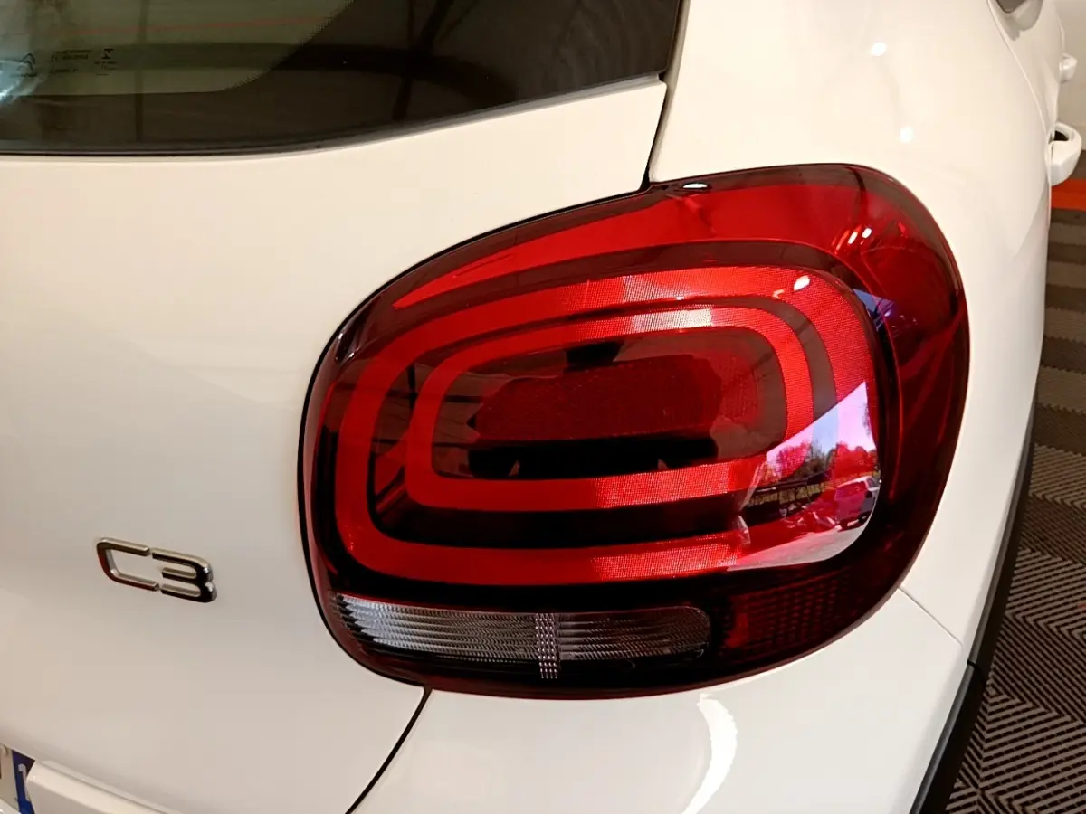 Gros plan sur le feu arrière droit rouge d'une Citroën C3 blanche, mettant en valeur le logo C3 sur la carrosserie.