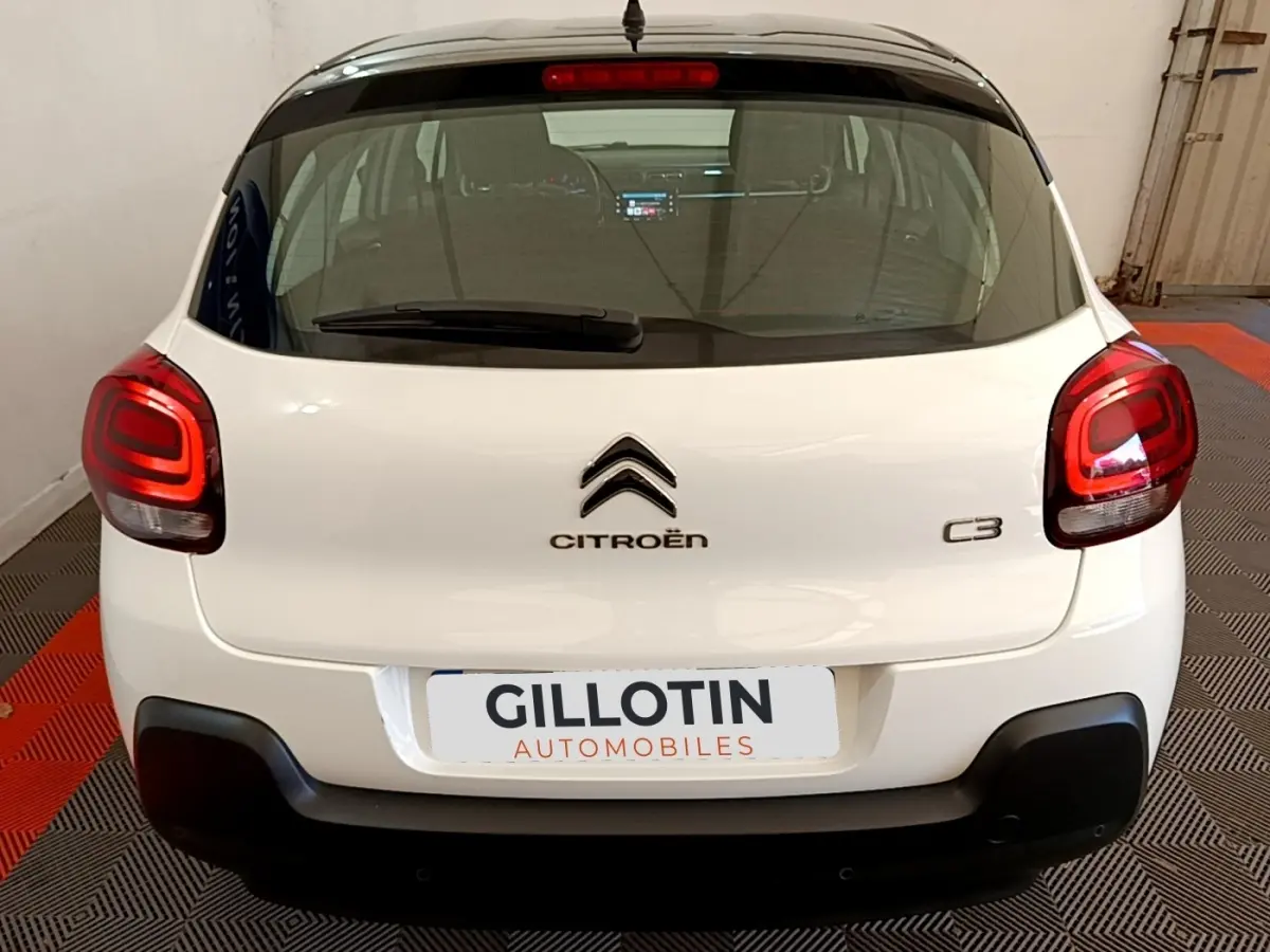 Vue arrière d'une Citroën C3 blanche avec feux arrière LED et logo centré dans un garage.