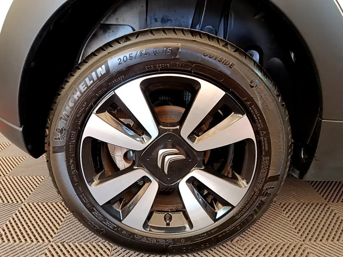 Gros plan sur la roue avant droite d'une Citroën C3 blanche, mettant en valeur la jante alliage bicolore et le pneu Michelin.
