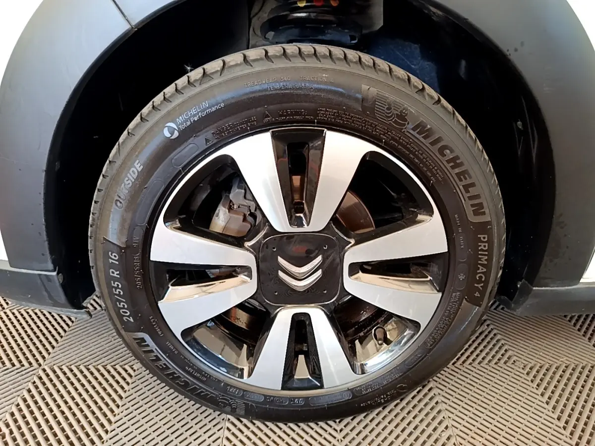 Gros plan sur la roue avant droite d’une Citroën C3 blanche, mettant en valeur la jante alliage bicolore et le pneu Michelin.