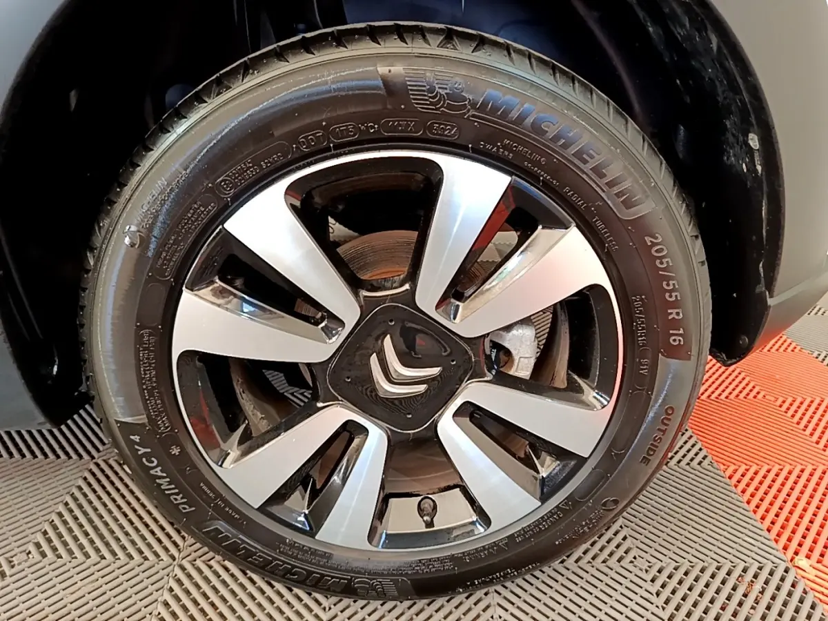 Gros plan sur la roue avant droite d'une Citroën C3 blanche, mettant en valeur la jante alliage et le pneu Michelin.