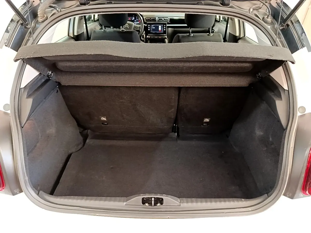 Coffre ouvert vu de l'arrière d'une Citroën C3 blanche, montrant l'espace de chargement et l'intérieur noir.