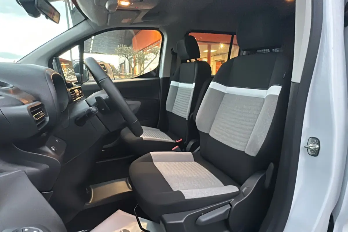 Vue intérieure côté conducteur du Citroën Berlingo 2025 avec sièges tissu bicolores gris et noir.