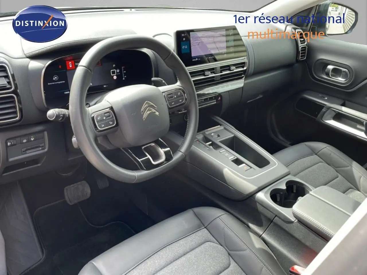 Vue intérieure côté conducteur du Citroën C5 Aircross Hybrid 136ch 2025, tableau de bord et volant multifonction noirs.