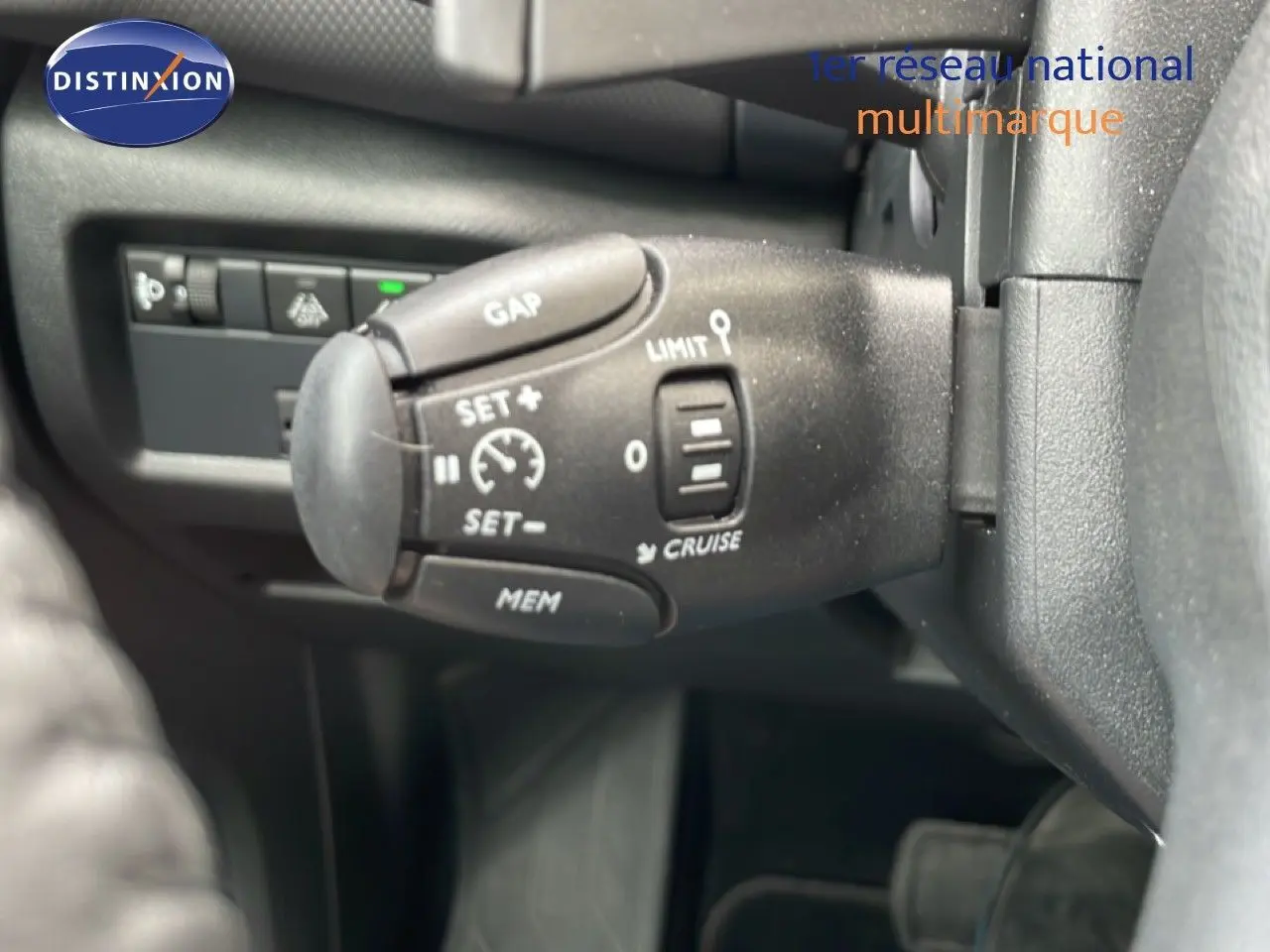 Gros plan sur la commande de régulateur de vitesse à gauche du volant dans l'habitacle du Citroën C5 Aircross gris platinium.