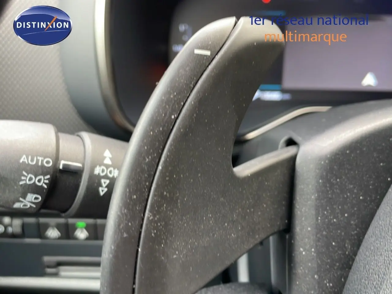 Gros plan sur la commande au volant noir du Citroën C5 Aircross Hybrid 2025, avec détails des commandes d'éclairage visibles.