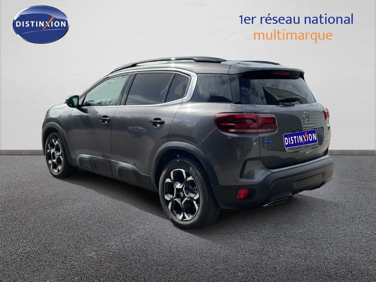 Vue 3/4 arrière droite d'un Citroën C5 Aircross Hybrid gris platinium métallisé avec jantes distinctives et toit noir.
