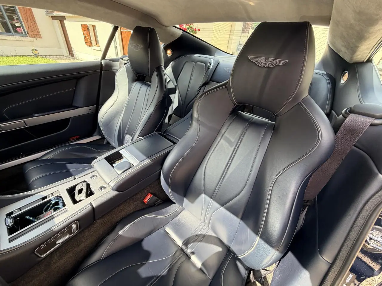 Intérieur de l'Aston Martin DB9 2016, vue côté droit sur sièges sport en cuir noir avec logo Aston Martin brodé.