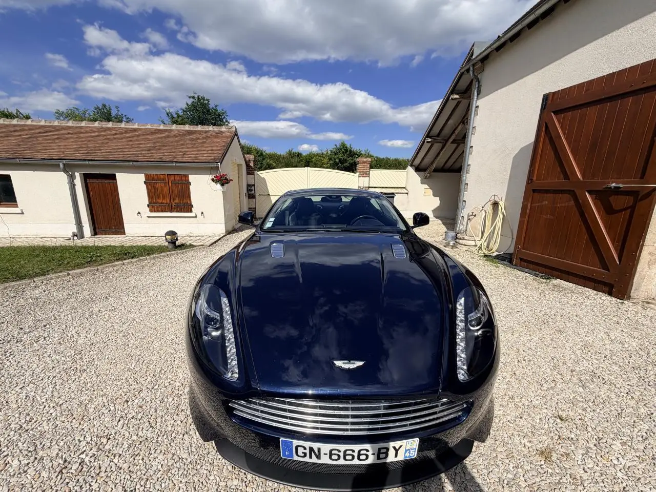 Vue avant d'une Aston Martin DB9 5.9 V12 2016 bleu foncé, avec calandre chromée et phares LED distinctifs.
