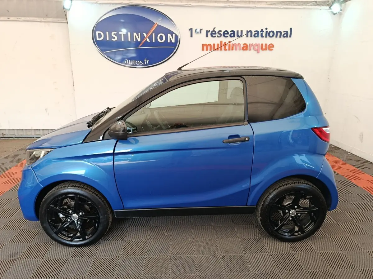 Vue de profil côté gauche d'une Aixam Ambition 0.5 City Sport 2024 bleu avec rétroviseur conducteur noir et jantes noires.