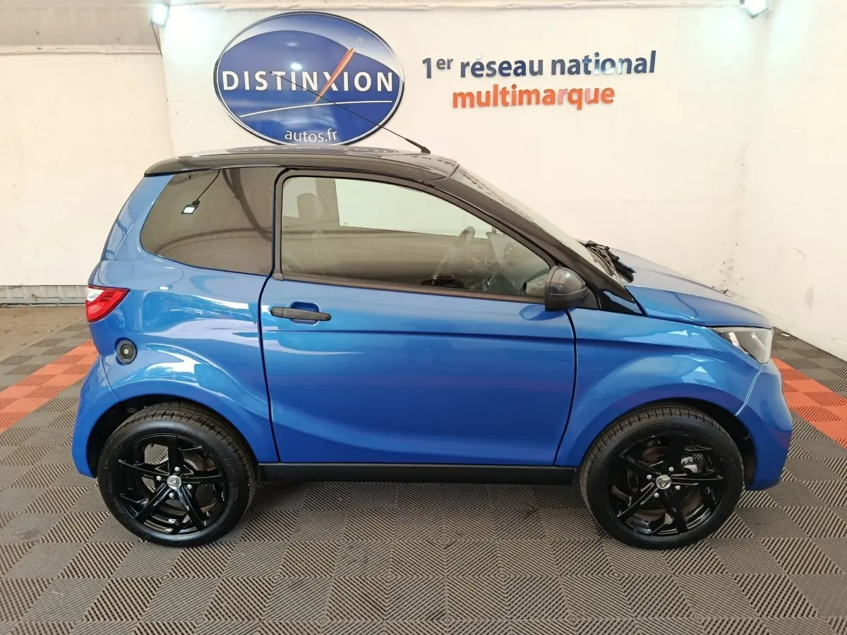 Vue de profil côté gauche d'une Aixam Ambition 0.5 City Sport 2024 bleu avec jantes noires et rétroviseur conducteur.