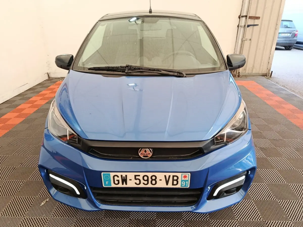 Vue avant d'une Aixam Ambition 0.5 City Sport 2024 bleu avec rétroviseur côté gauche et feux LED diurnes allumés.