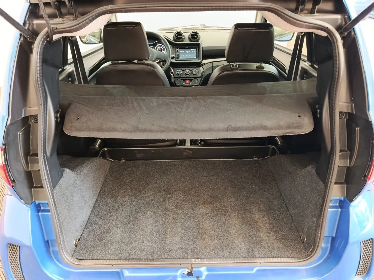 Coffre ouvert d’une Aixam Ambition 0.5 City Sport bleu, vue arrière montrant l’intérieur et tableau de bord.