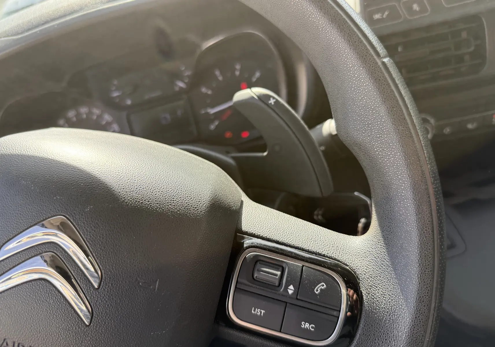 Gros plan sur le volant noir du Citroën Berlingo 2019 avec commandes intégrées et palettes de changement de vitesse.