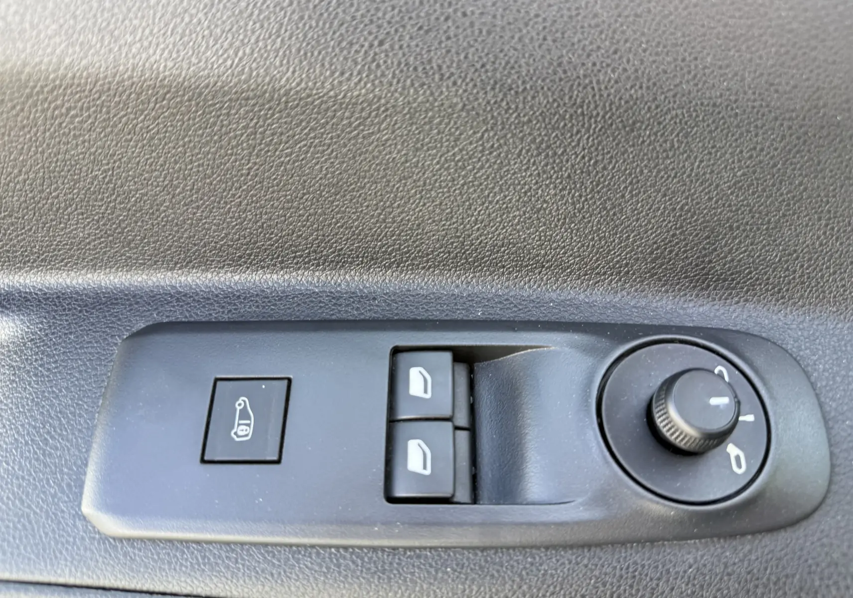 Gros plan sur les commandes de réglage des rétroviseurs et des vitres électriques côté conducteur du Citroën Berlingo beige.