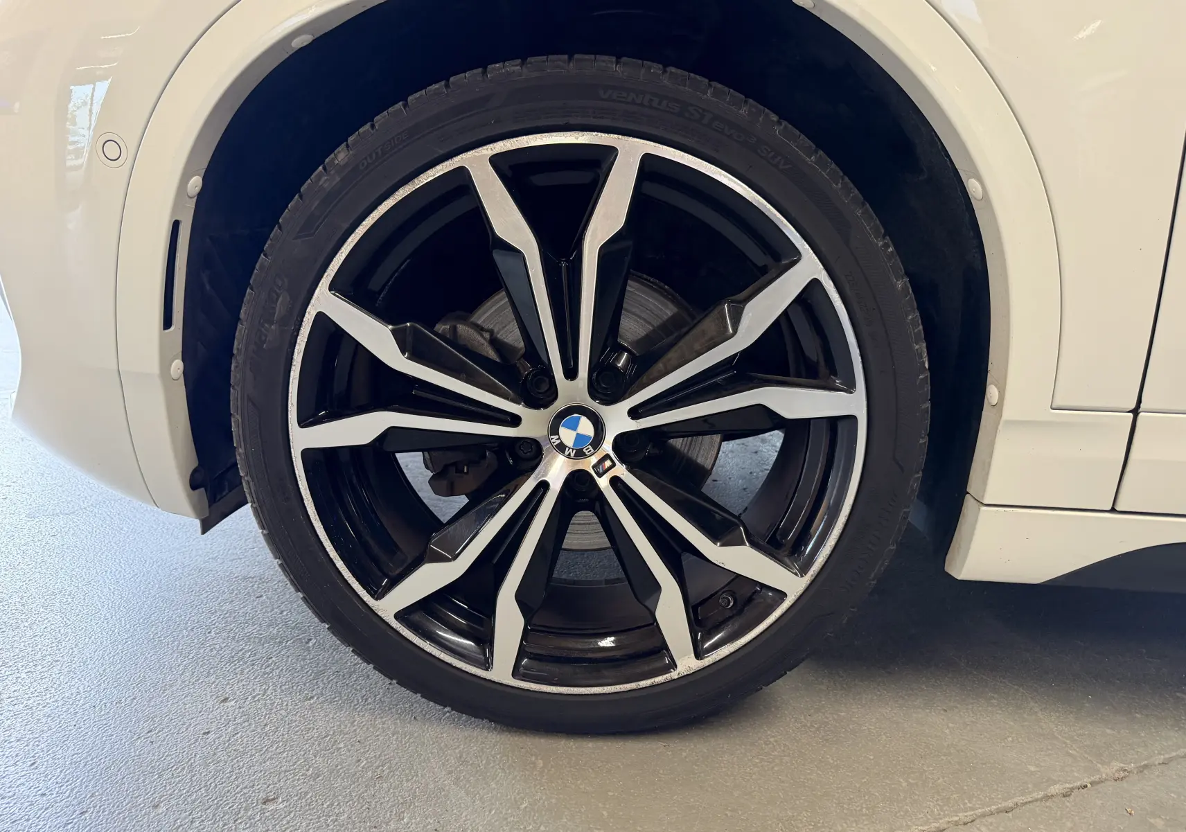 Gros plan sur la jante alu 19 pouces bicolore noire et argentée du côté arrière droit d'un BMW X2 blanc.