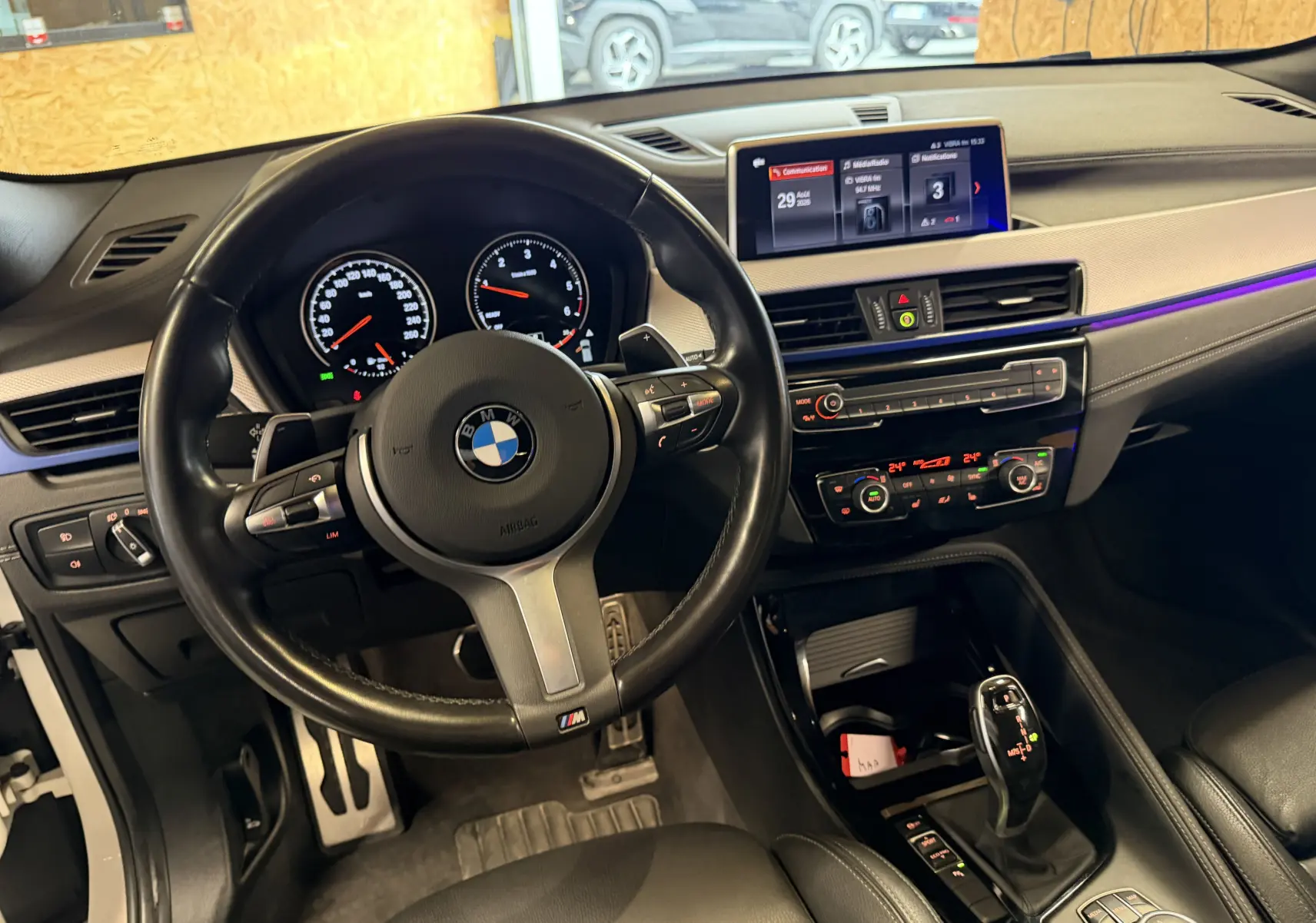 Vue intérieure du poste de conduite de la BMW X2 sDrive18d 2023, volant cuir M Sport et tableau de bord digital.