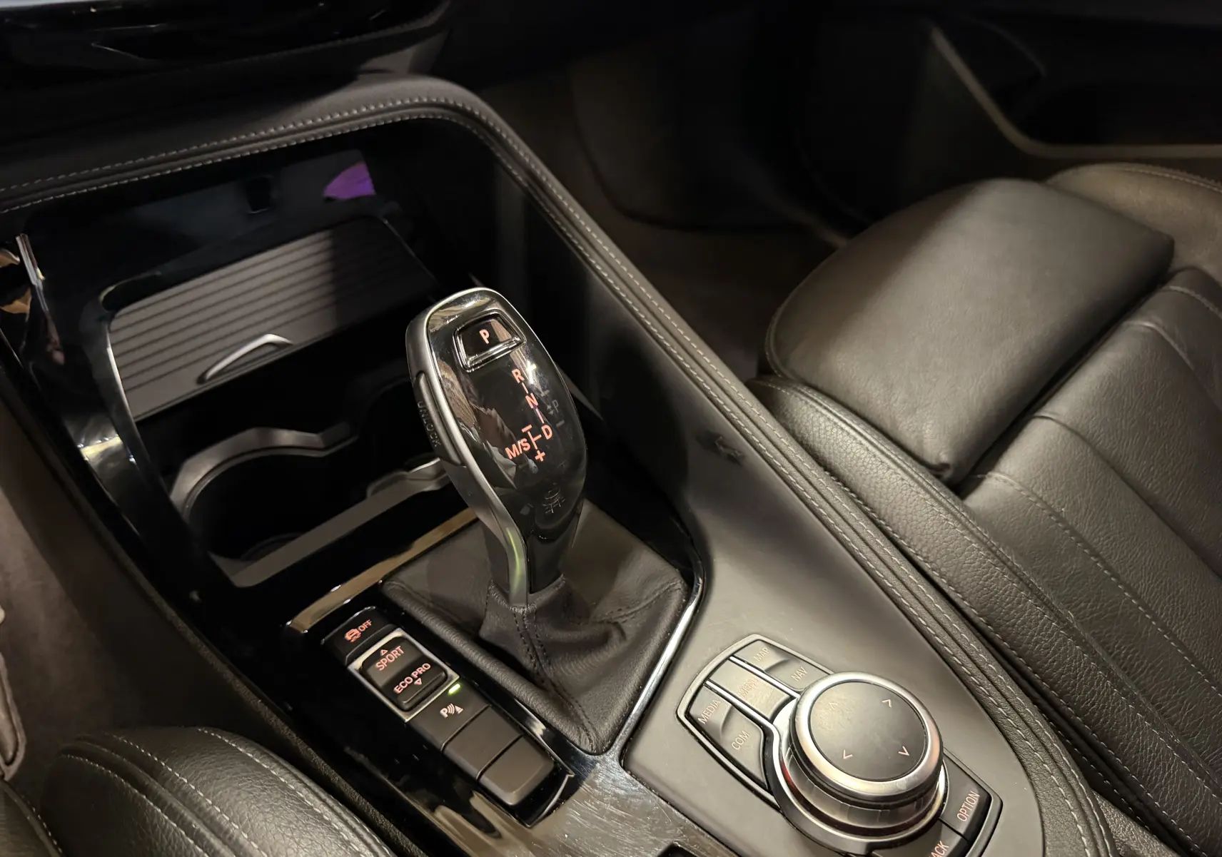 Gros plan sur la console centrale noire du BMW X2 2023 avec levier de vitesses automatique et commandes multifonctions.