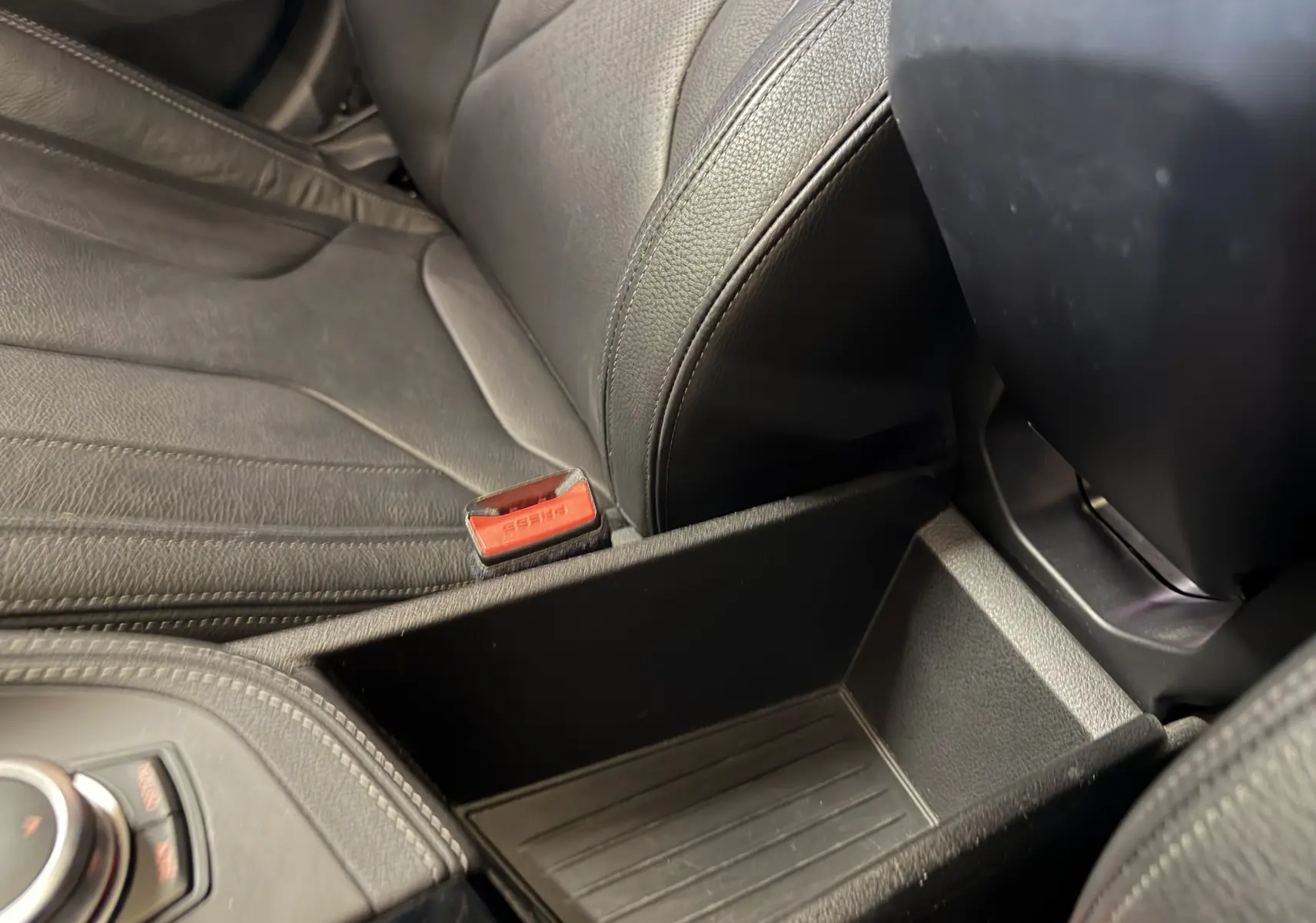 Gros plan intérieur sur le rangement central et siège en cuir noir de la BMW X2 sDrive18d 2023.