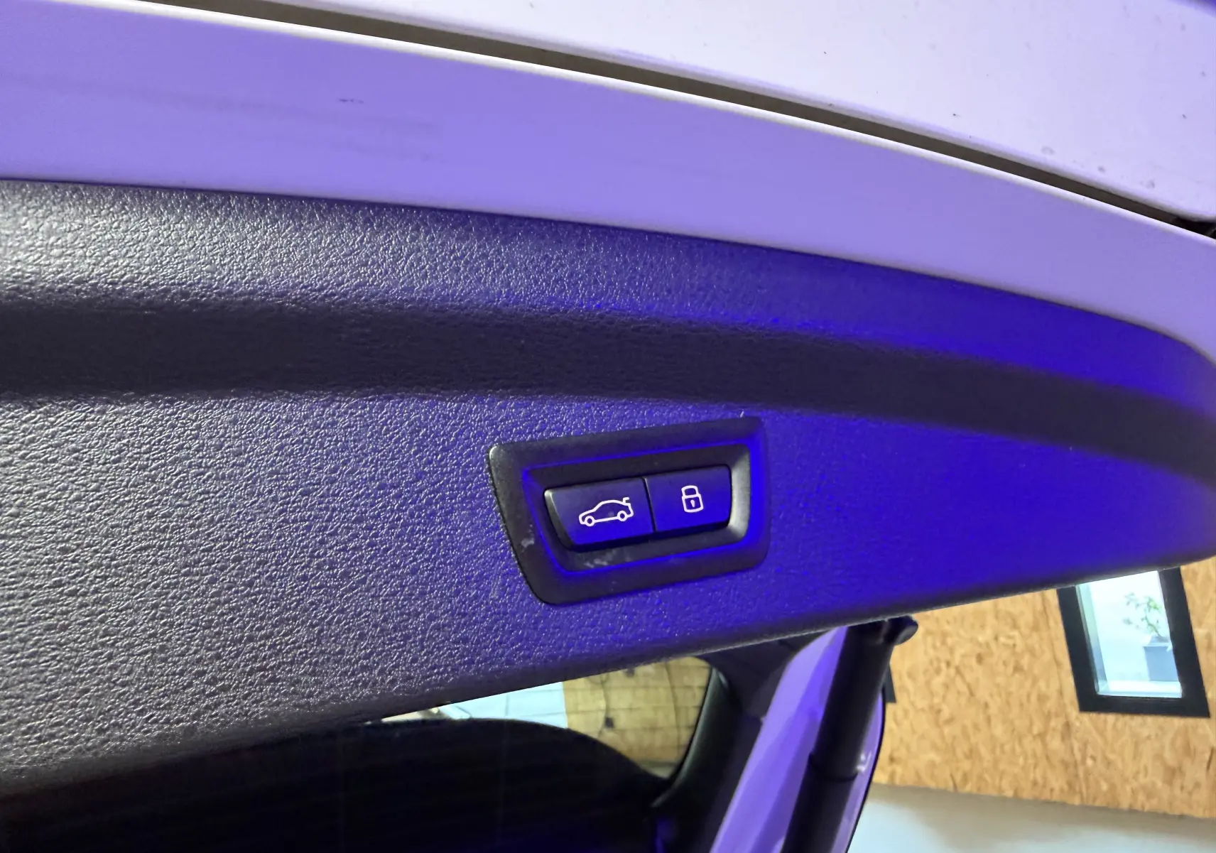 Gros plan sur les boutons de commande électrique du hayon du BMW X2 blanc, intérieur du coffre visible.