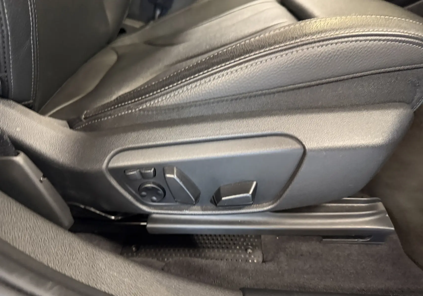 Détail du siège conducteur noir avec commandes électriques de réglage sur BMW X2 sDrive18d 2023.