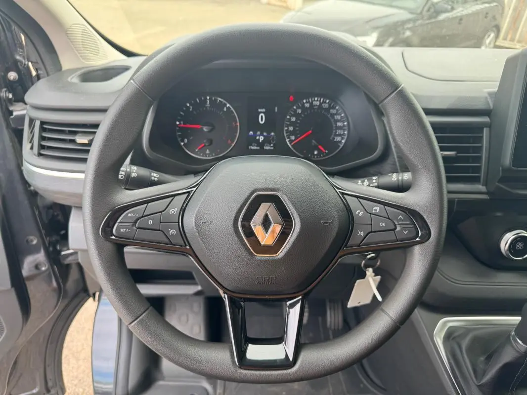 Vue intérieure centrée sur le volant noir du Renault Trafic Fourgon 2024 avec tableau de bord et commandes visibles.