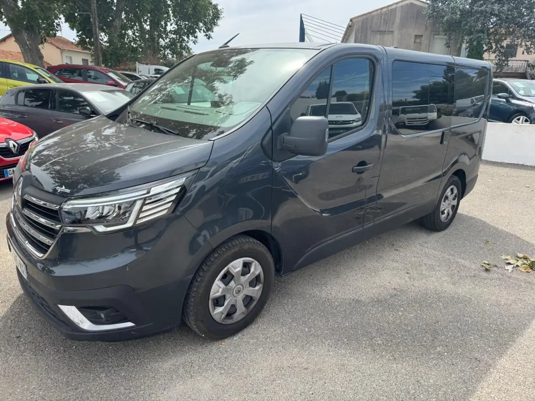 Renault Trafic Fourgon gris foncé vu en 3/4 avant droit avec vitres surteintées et porte latérale visible.