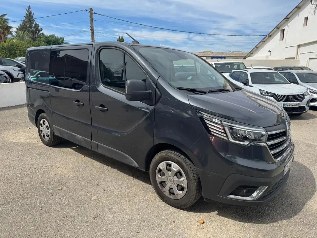Renault Trafic Fourgon gris foncé vu en 3/4 avant droit avec vitres surteintées et porte latérale visible.