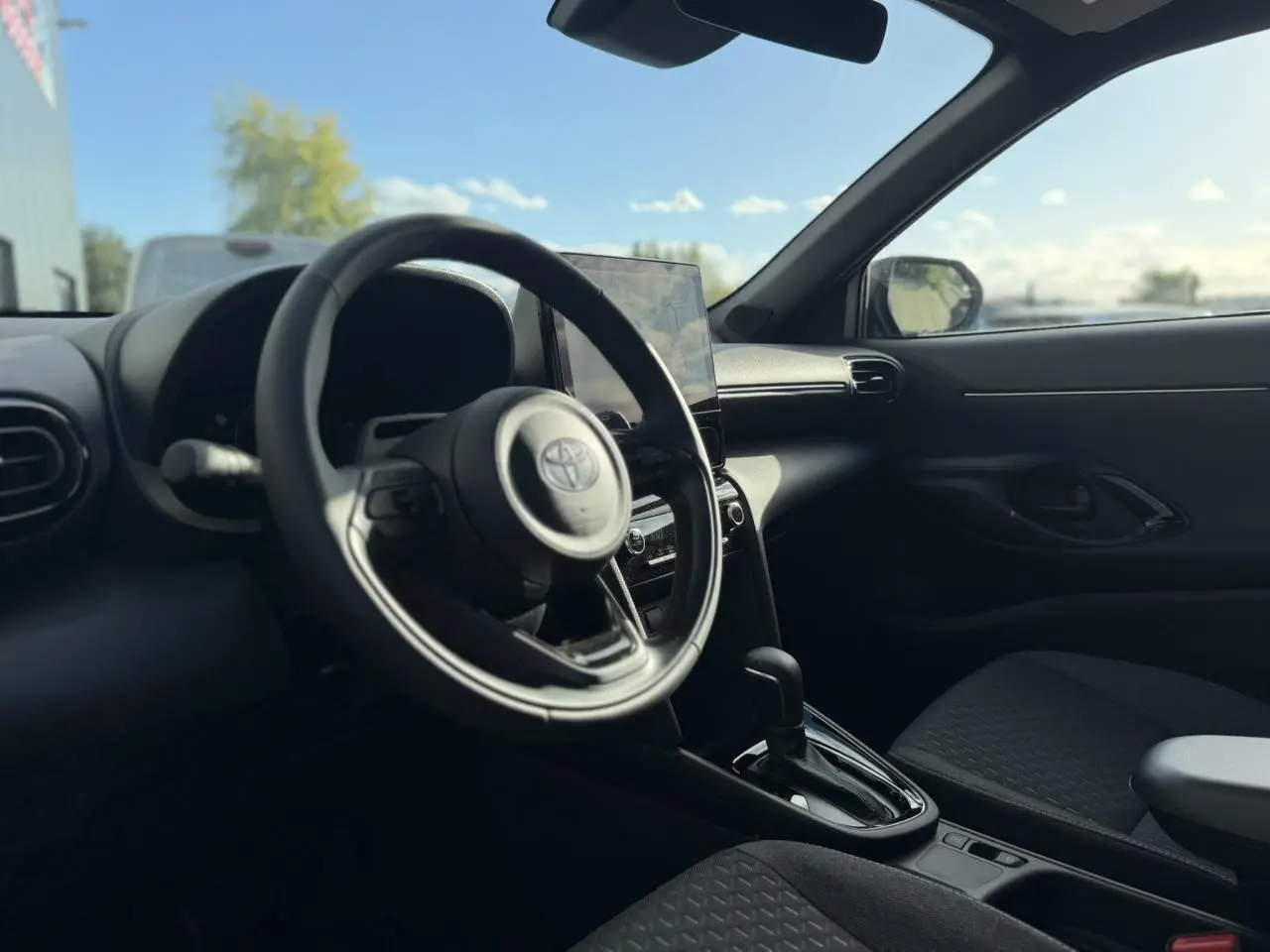 Intérieur avant droit de la Toyota Yaris Cross gris Atlas 2026, volant cuir et écran tactile central visible.