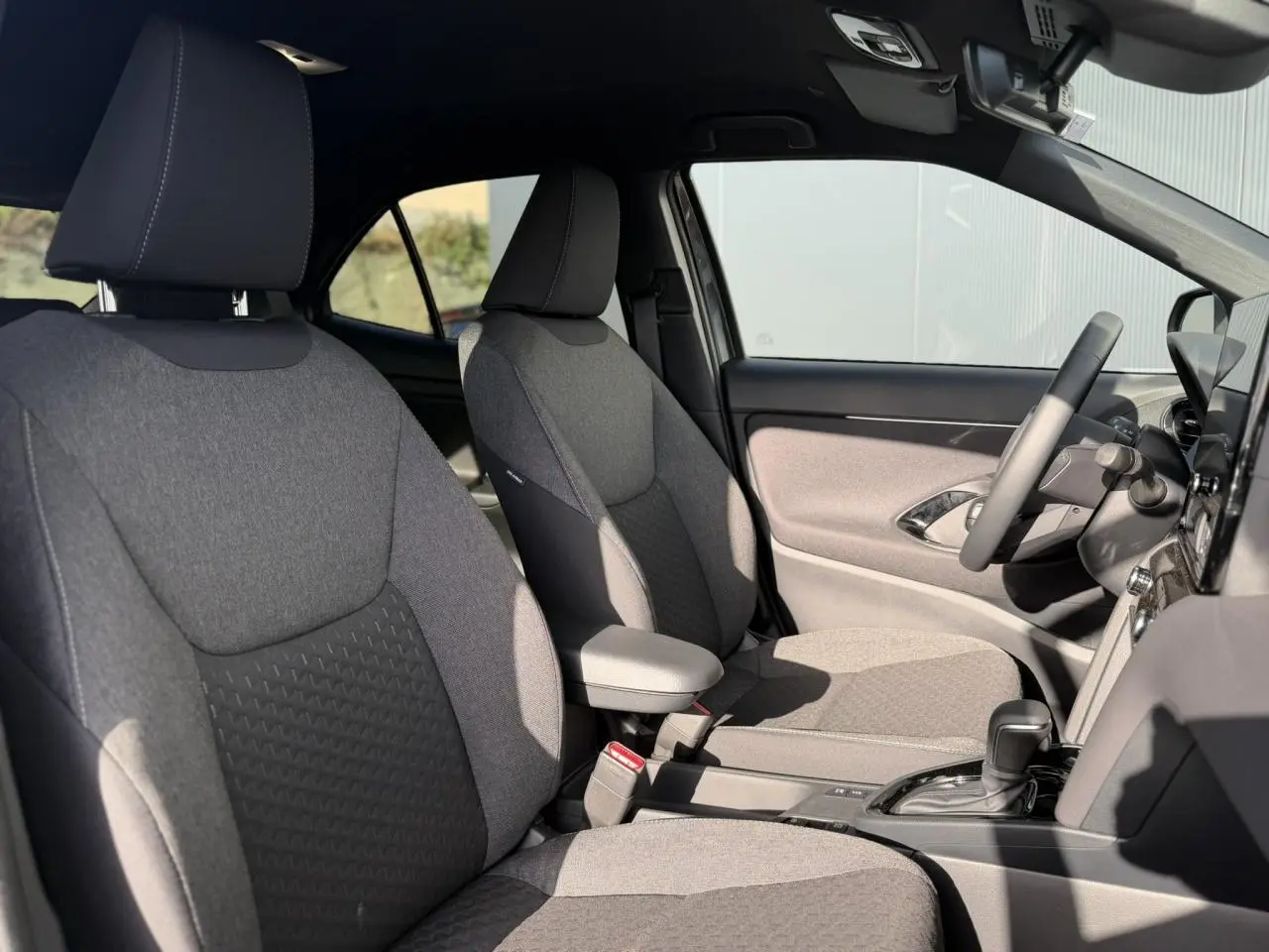 Vue intérieure côté droit montrant les sièges avant gris et le volant multifonctions du Toyota Yaris Cross 2026.