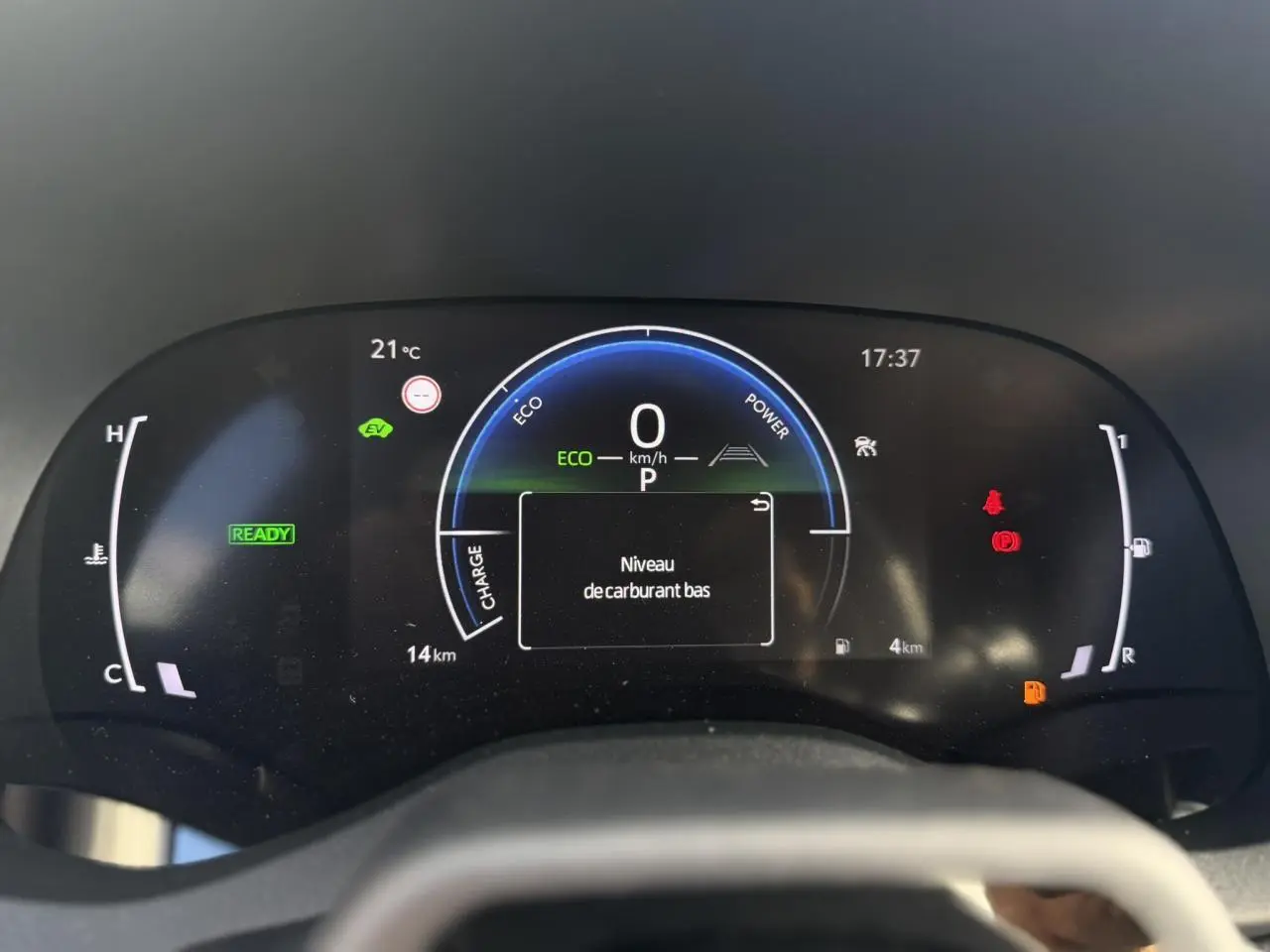 Vue rapprochée du tableau de bord numérique de la Toyota Yaris Cross 2026 affichant un avertissement de niveau de carburant bas.