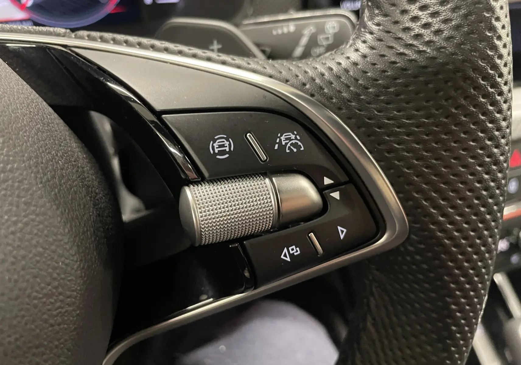 Gros plan sur les commandes de régulateur de vitesse au volant perforé d'une Skoda Scala 2025.