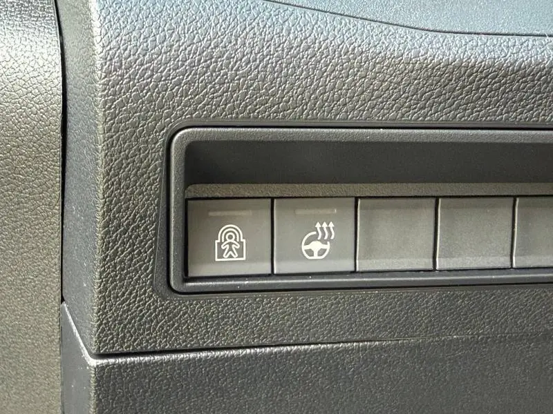 Gros plan sur les boutons de commande noirs du tableau de bord du Citroën Berlingo 2025, version Sirkka Green.