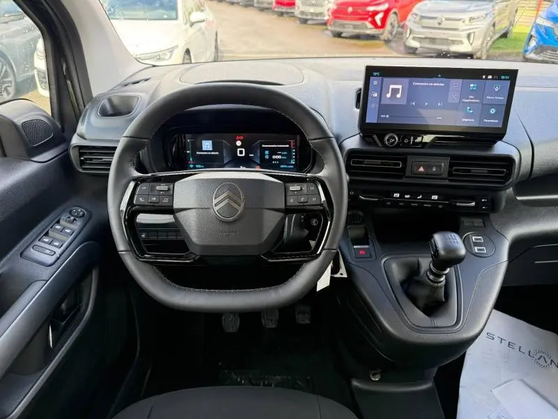 Vue intérieure frontale du poste de conduite du Citroën Berlingo 2025 avec volant multifonction et écran tactile central.