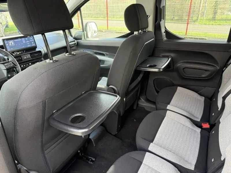 Vue intérieure arrière droite du Citroën Berlingo 2025 Sirkka Green avec tablette rabattable et sièges bi-ton gris et noir.