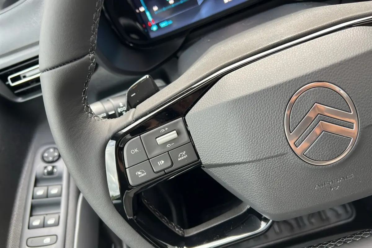 Gros plan sur le volant cuir multifonctions du Citroën Berlingo 2025 avec commandes intégrées et logo chromé central.