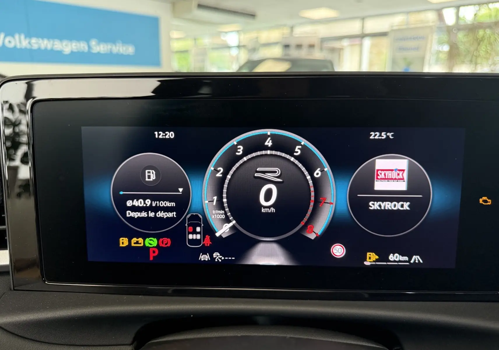 Écran numérique du tableau de bord du Volkswagen T-Roc R-Line noir, affichant vitesse, consommation et radio Skyrock.