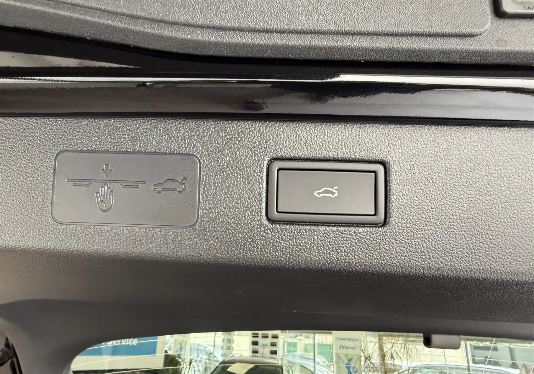 Gros plan sur le bouton d'ouverture électrique du coffre du Volkswagen T-Roc R-Line noir intense, vue intérieure du hayon ouvert.