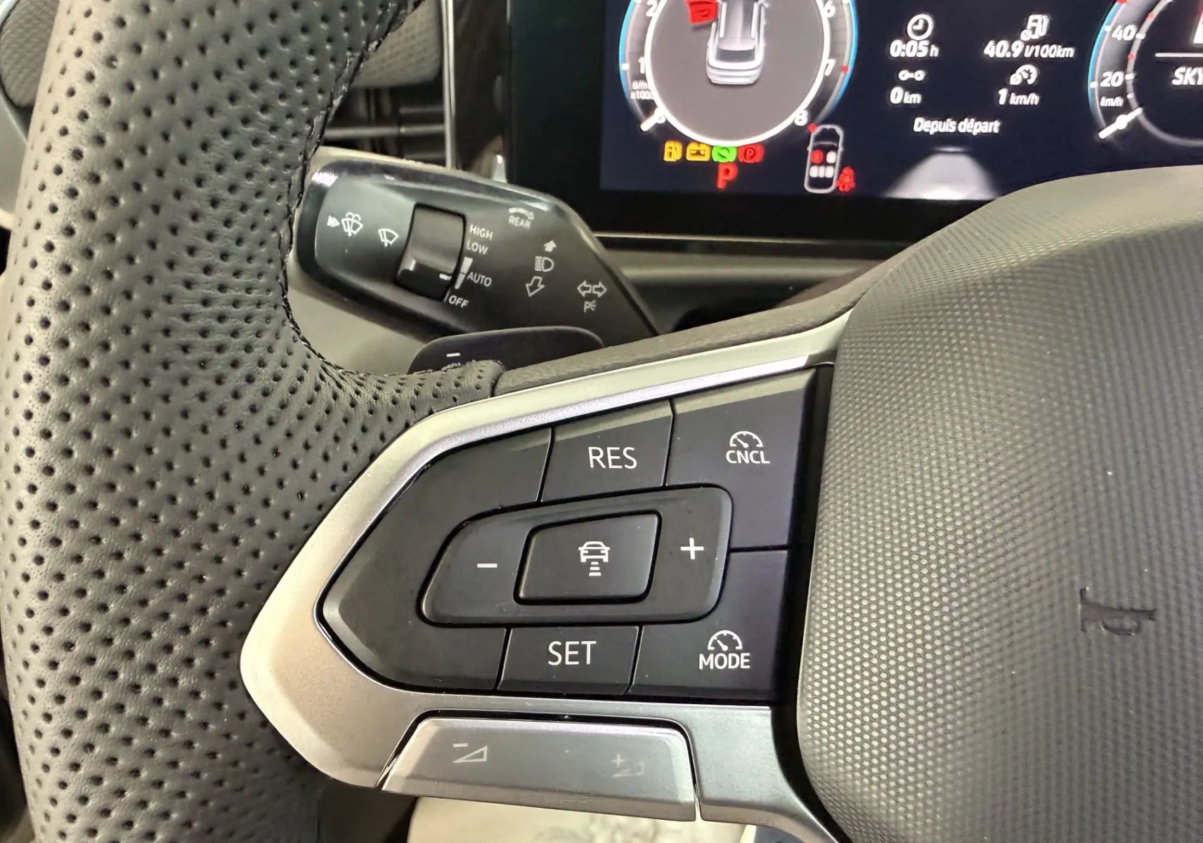 Gros plan sur le volant noir perforé du Volkswagen T-Roc R-Line 2026 avec commandes de régulateur de vitesse visibles.